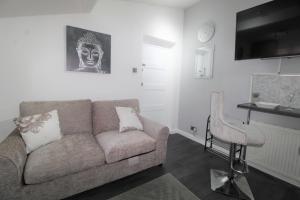 a living room with a couch and a chair at Studio 2 min walk to Upton Park Station in London +3 photos