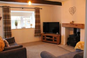 a living room with a flat screen tv and a couch at Bumblebee Cottage nestled in stunning countryside. in Barrowford