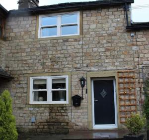 a brick house with a door and two windows at Bumblebee Cottage nestled in stunning countryside. in Barrowford