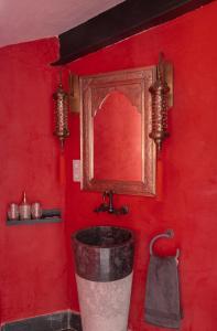 Baño rojo con cubo y espejo en RIAD MEDINA MUDEJAR BAÑOS ARABES en Toledo