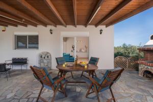 a patio with a table and chairs and a fireplace at Villa Cleronomia, private pool, seaview, in Kaloudhianá