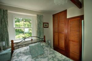 Schlafzimmer mit einem Bett und einem Fenster in der Unterkunft Characterful 2 bed cottage in excellent location in Baslow
