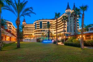 a large building with palm trees in front of it at Kirman Leodikya Resort in Okurcalar