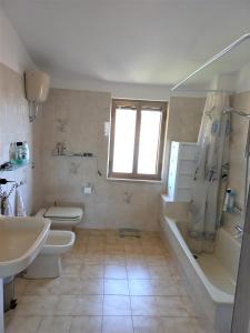 een badkamer met 2 toiletten, een bad en een wastafel bij The Englishmans Home in Cuglieri