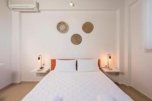 a white bedroom with a white bed and two lamps at Villa Cleronomia, private pool, seaview, in Kaloudhianá