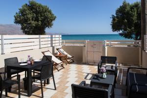 a patio with tables and chairs and a view of the ocean at Wink Bnb Paraliaki in Kissamos