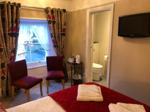 a bedroom with a bed and two chairs and a window at Tarn Hows in Keswick