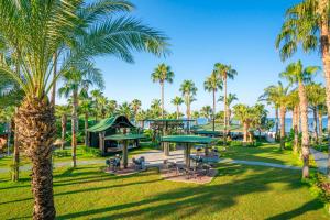 a park with palm trees and picnic tables at Kirman Arycanda De Luxe in Okurcalar