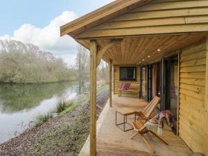 a wooden deck with two chairs next to a lake at Willow in Rugby