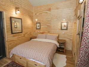 a bed in a small room with wooden walls at Willow in Rugby