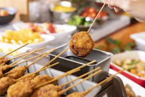 a person holding a fried food on a stick at Hotel Wing International Premium Osaka-Shinsekai in Osaka