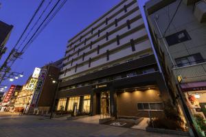 un bâtiment situé dans une rue de la ville la nuit dans l'établissement Hotel Wing International Premium Osaka-Shinsekai, à Osaka
