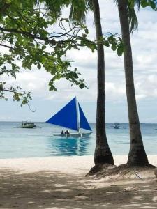 a sail boat in the water with two palm trees at Tara staycation unit in Boracay