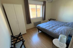 ein Schlafzimmer mit einem blauen Bett und einem Fenster in der Unterkunft Maison avec véranda - Gîte de l'Arbrisseau in Rethel