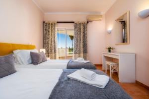 a bedroom with two beds and a desk and a window at Colina Verde Resort in Moncarapacho