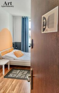uma porta que leva a um quarto com uma cama em Art Apartamenty 2 em Kalisz