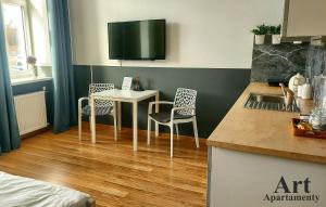 cocina con mesa y sillas y TV en Art Apartamenty 2, en Kalisz