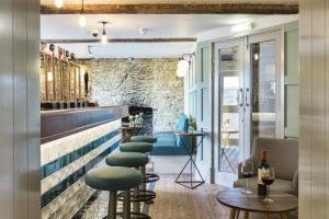 a bar with green stools and a stone wall at The Old Stocks Inn in Stow on the Wold
