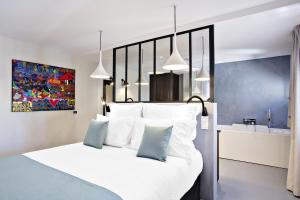 Schlafzimmer mit einem Bett mit weißer Bettwäsche und blauen Kissen in der Unterkunft Villa du Taur in Toulouse