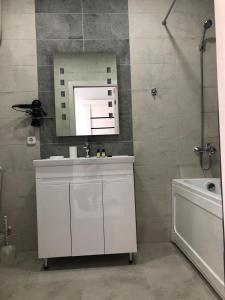 ein Badezimmer mit einem Waschbecken, einem Spiegel und einer Badewanne in der Unterkunft Новая современная квартира в центре города in Qostanai