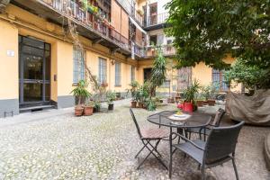 un patio con tavolo e sedie di fronte a un edificio di Piazza Statuto Comfy APT - with 2 Balconies a Torino