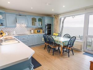 a kitchen with blue cabinets and a table with chairs at Rocklea Seaside Cottage in Newcastle
