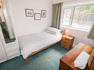 a bedroom with a bed and a table and a window at Rocklea Seaside Cottage in Newcastle