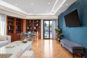 a living room with a couch and a tv on a wall at Acropolis Prestige Residence in Athens