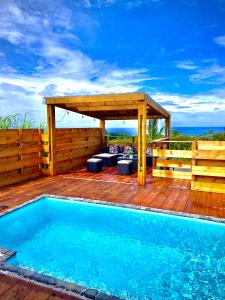 - une piscine sur une terrasse en bois avec une pergola dans l'établissement La Villa Horizon, à Rivière du Rempart