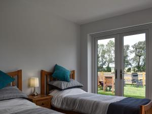 a bedroom with two beds and a sliding glass door at Lords View in Ruckinge