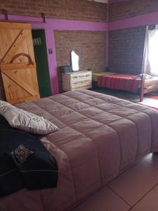 1 dormitorio con 1 cama grande y puerta de madera en Casa de huéspedes La vista en El Hoyo