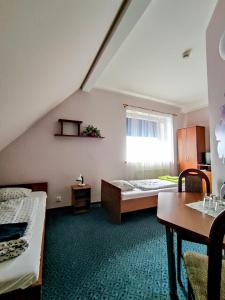 Habitación con 2 camas, mesa y ventana en Hotel Na Wzgórzu en Gniew