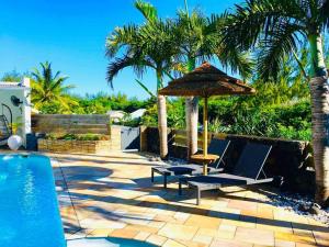 - une terrasse avec 2 chaises et un parasol à côté de la piscine dans l'établissement la kaz Australe, pointe de langevin, à Saint-Joseph