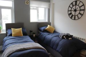 een slaapkamer met 2 bedden en een klok aan de muur bij Superb Studio Flats in City Centre in Southampton