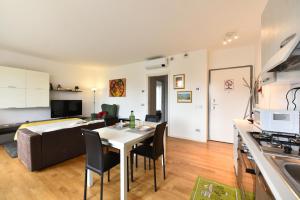una cucina e un soggiorno con tavolo e divano di CaseOspitali - Casa Kikka elegante appartamento con balcone in nuovo condominio a Cernusco sul Naviglio