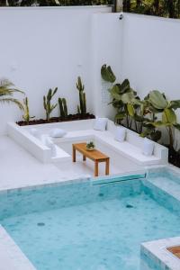 uma sala de estar com um sofá e uma mesa ao lado de uma piscina em Olisa Hotel Boutique em Maresias