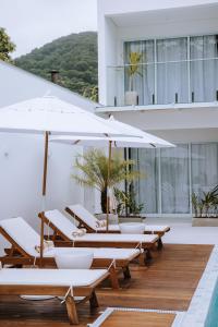 a group of lounge chairs and umbrellas on a building at Olisa Hotel Boutique in Maresias