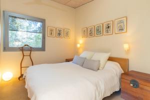 1 dormitorio con cama blanca y ventana en La casita del bosque, en Vilopríu