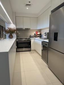 una cocina con armarios blancos y electrodomésticos de acero inoxidable en Magnolia- Dubai Creek Harbour Condo Apartment ApartHotel UAE, en Dubái