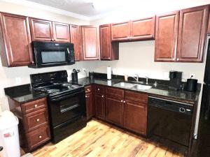 a kitchen with wooden cabinets and a black stove at Peaceful Townhouse Near Lake in Guntersville