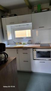 kuchnia z białymi szafkami, umywalką i oknem w obiekcie Chalet avec patio en Haute Corse 5 couchages w mieście Camp du Cap Sud