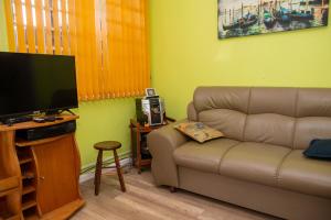 Il comprend un salon doté d'un canapé et d'une télévision à écran plat. dans l'établissement Linda casa a 950m do mar em Bertioga SP, à Bertioga