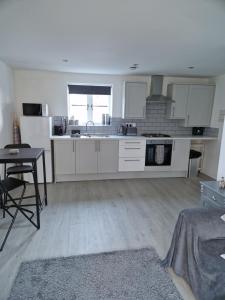 a kitchen with white cabinets and a table in it at The Lodge, 9 Dene House in Gateshead