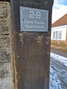 ein Schild an der Seite eines steinernen Hauses in der Unterkunft The Lodge, 9 Dene House in Gateshead