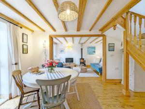 a dining room with a table and chairs and a living room at Stable Cottage in Woodmancote