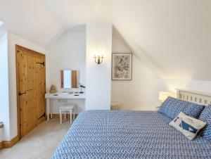 a bedroom with a blue bed and a desk at Stable Cottage in Woodmancote