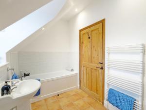 uma casa de banho com um lavatório e uma banheira em Stable Cottage em Woodmancote