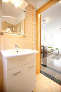 ein Badezimmer mit einem weißen Waschbecken und ein Wohnzimmer in der Unterkunft Apartments Stadthaus Briski in Opatija