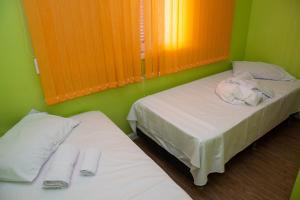 - 2 lits dans une chambre orange et verte dans l'établissement Linda casa a 950m do mar em Bertioga SP, à Bertioga