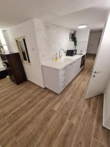 a kitchen with white cabinets and a wooden floor at Cohens apartments in Jerusalem